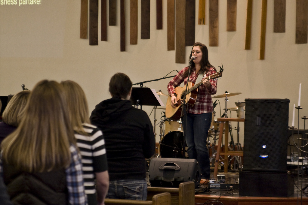 woman leading worship with guitar at church